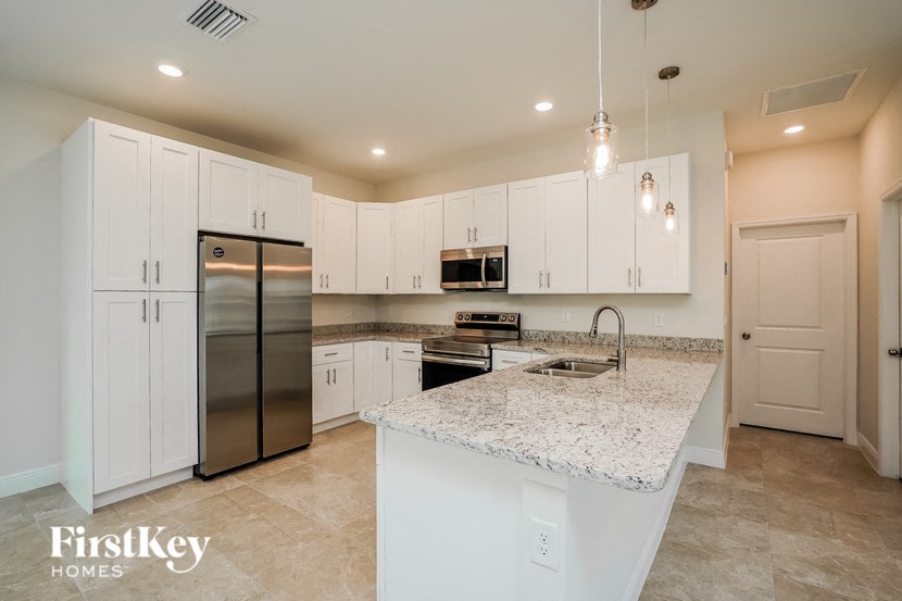 a white kitchen with stainless steel appliances and granite counter tops