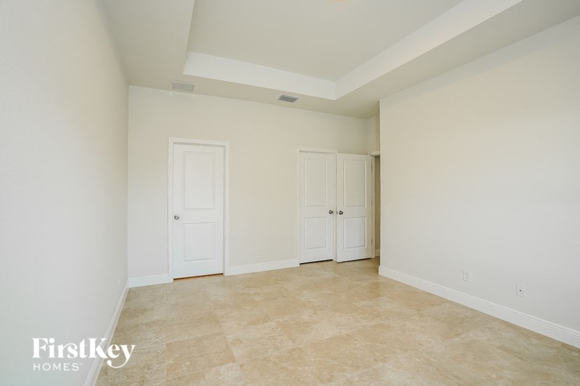 an empty living room with white doors and a tile floor