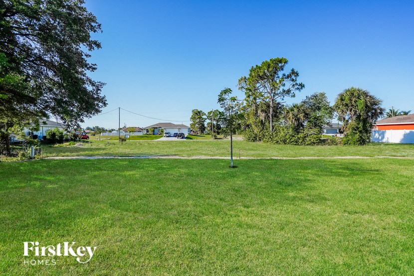 a park with a green field and a house in the background