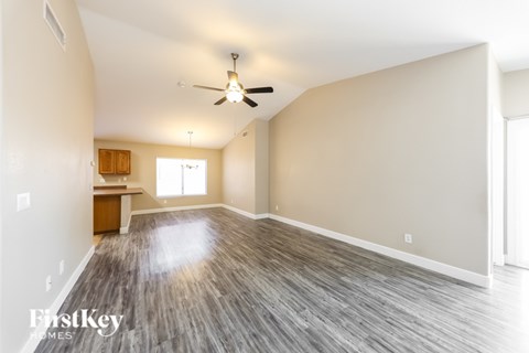 A spacious room with a ceiling fan and wooden flooring.