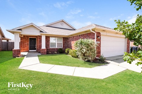 a small brick house with a lawn and a driveway