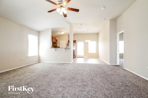 an empty living room with a ceiling fan and carpet