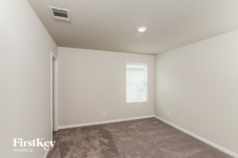 the living room of a house with carpet and a window