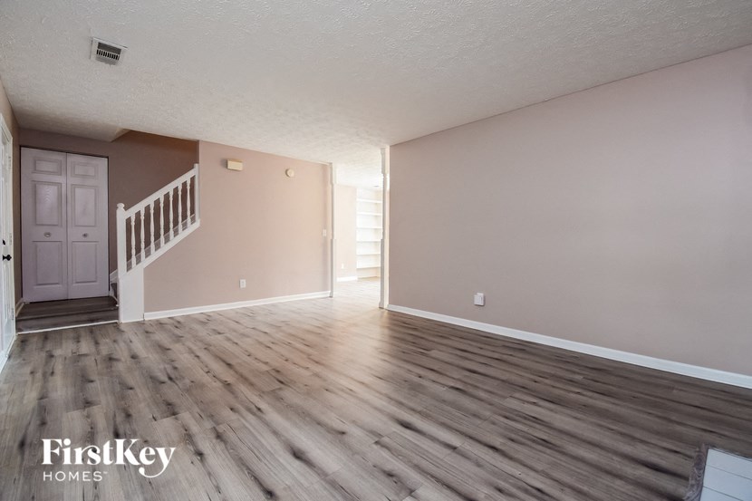 the living room of an empty house with wooden floors and a staircase