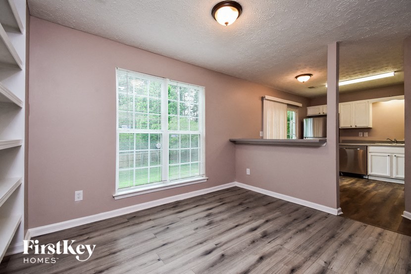 an empty living room with a large window and a kitchen