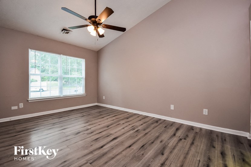 the spacious living room with wood floors and a ceiling fan