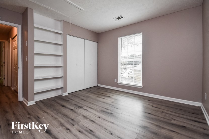 a bedroom with a closet and a window and wooden floors