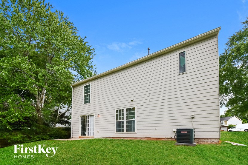 the side of a white house with a mailbox on the grass