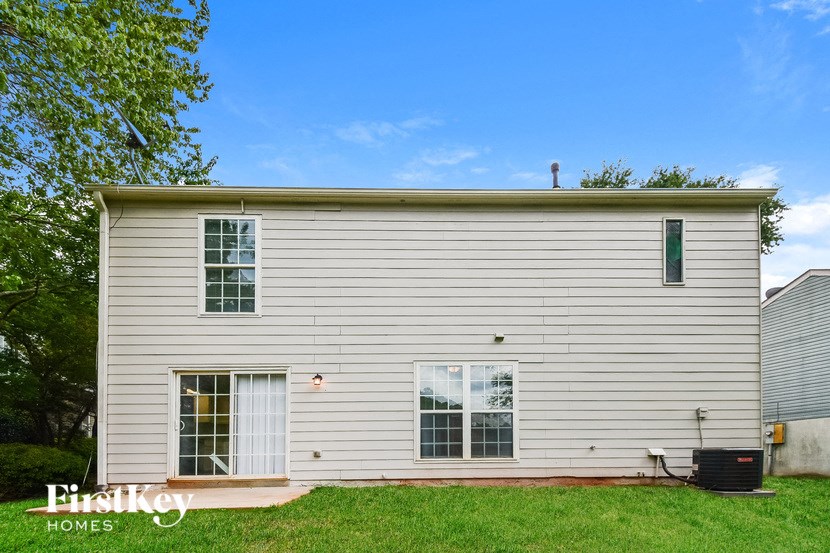 the side of a white house with a yard and a blue sky