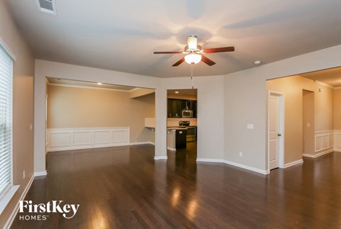 A spacious living room with a ceiling fan and hardwood floors.