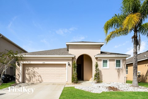 a house with a garage door and a palm tree