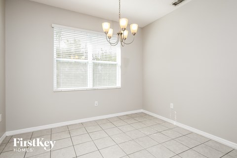 an empty dining room with a window and a chandelier