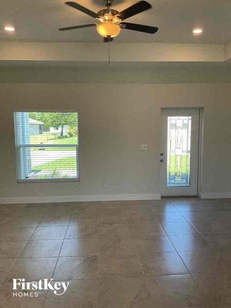 an empty living room with a ceiling fan and a door