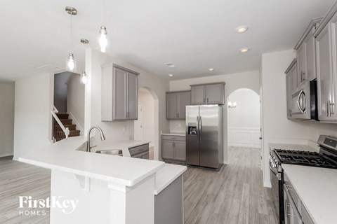 a white kitchen with stainless steel appliances and white counter tops
