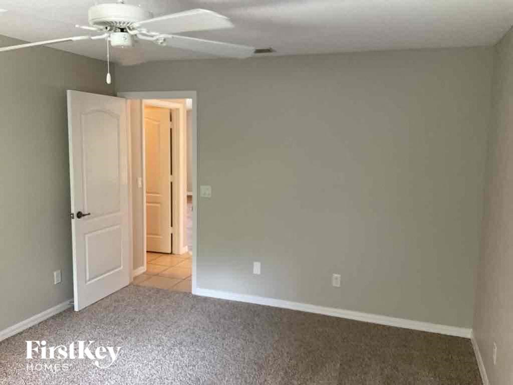 an empty living room with a white door and a ceiling fan