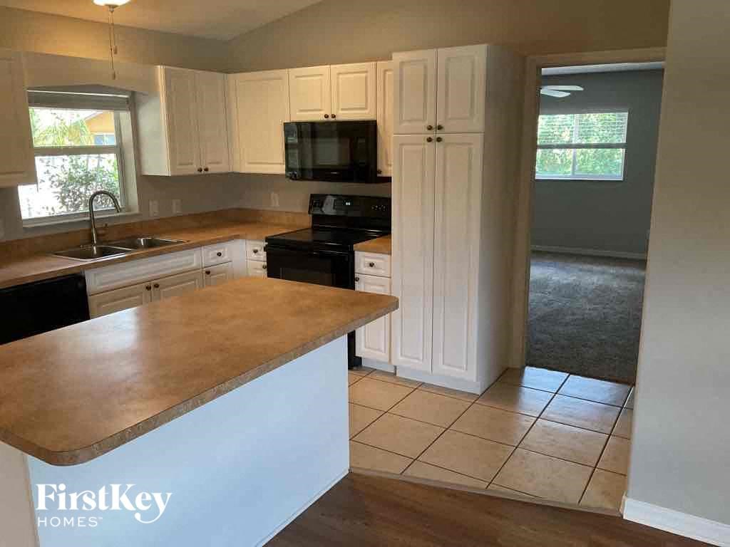 an empty kitchen with white cabinets and a counter top