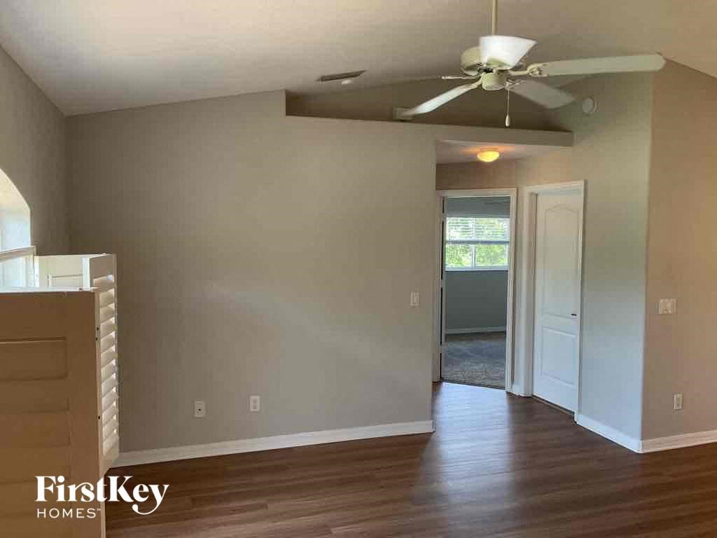an empty living room with wood floors and a ceiling fan