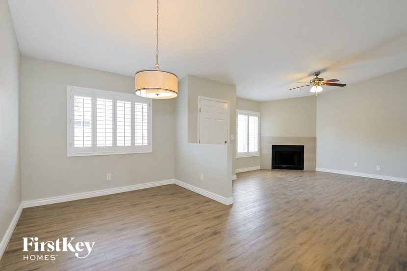 an empty living room with a fireplace and a ceiling fan