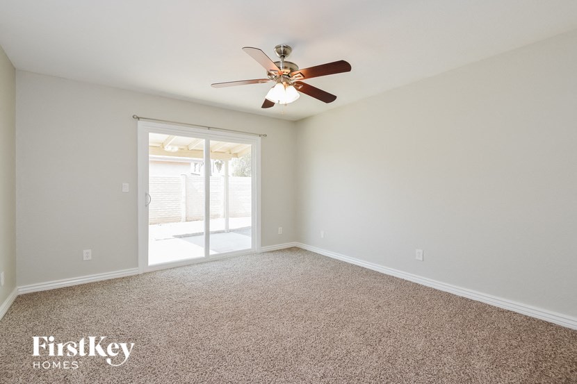 an empty living room with a ceiling fan and a door to a patio