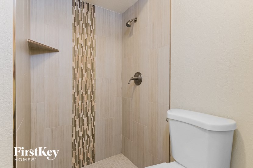 a tiled shower with a toilet in a bathroom