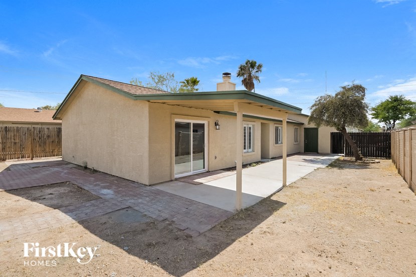 a small beige house with a driveway and a fence