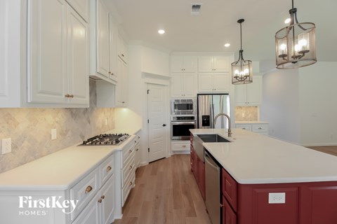 A kitchen with white cabinets and a marble countertop.