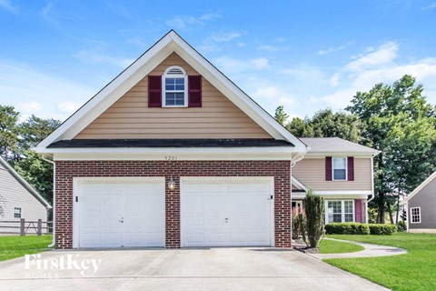 a brick house with two garage doors on a lawn