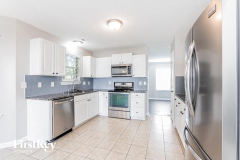 a large kitchen with stainless steel appliances and white cabinets