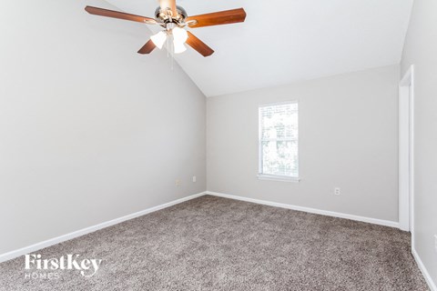 a bedroom with a ceiling fan and a carpet
