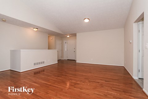 the living room and dining room with hardwood flooring and white walls