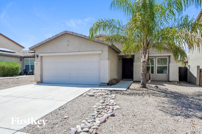 A house with a white garage door and a palm tree in front.