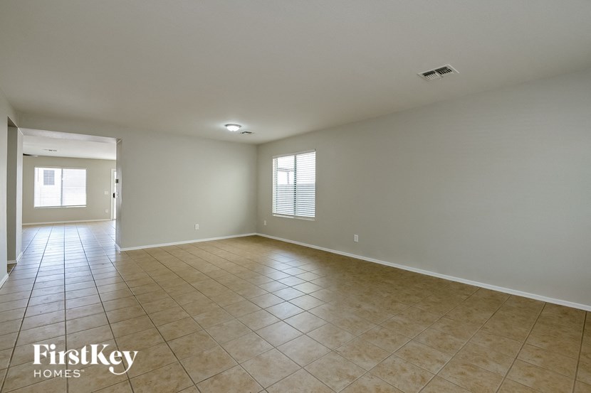 A spacious empty room with tiled flooring and white walls.