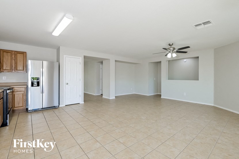 A spacious room with a kitchen area and a ceiling fan.