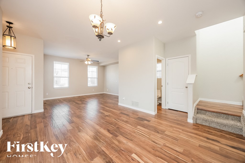 A room with wooden floors and a chandelier hanging from the ceiling.