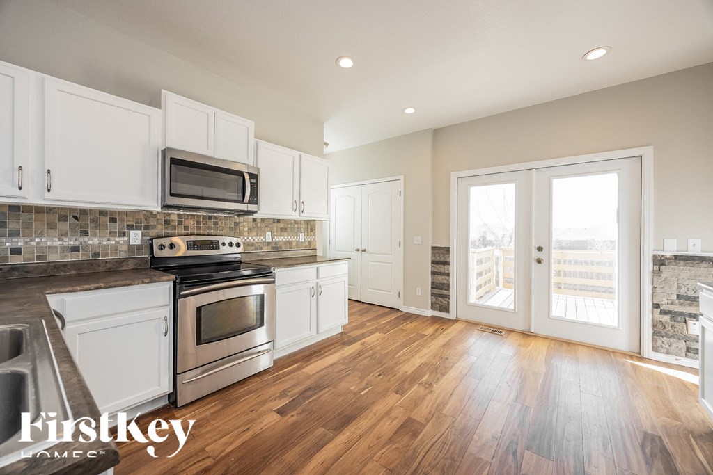 A kitchen with white cabinets and a wooden floor.