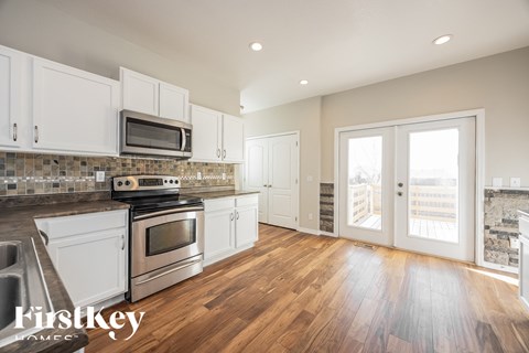 A kitchen with white cabinets and a wooden floor.