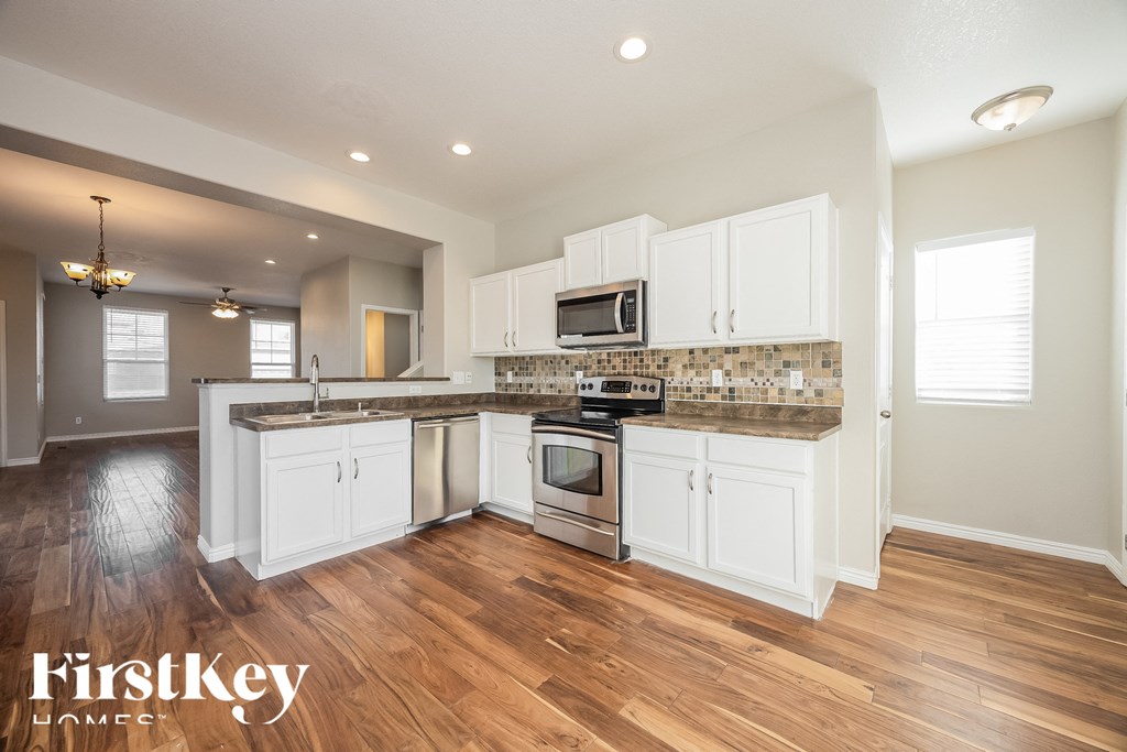 A kitchen with wooden floors and white cabinets.