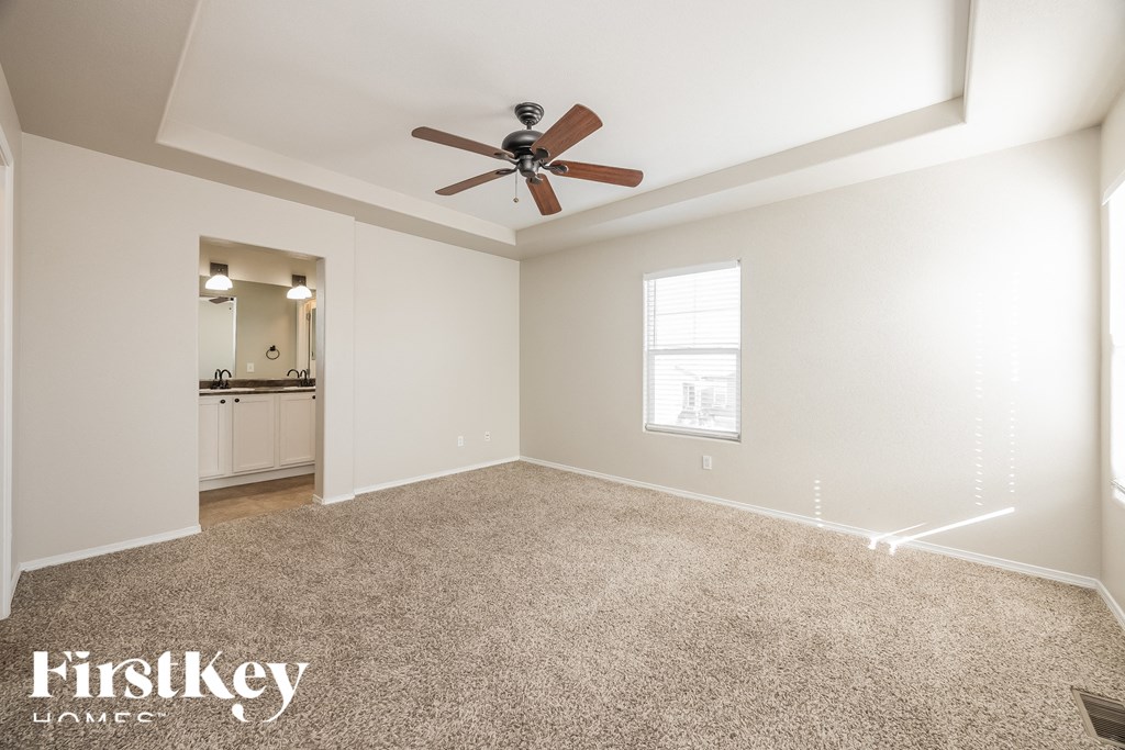 A spacious room with a ceiling fan and a carpeted floor.
