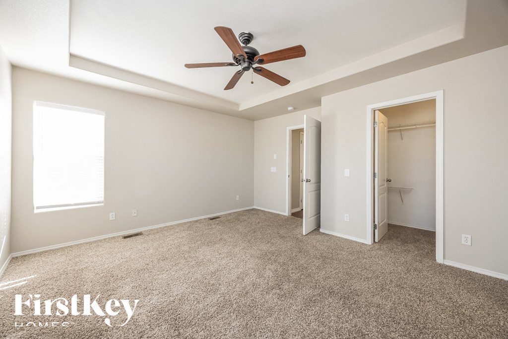 A spacious room with a ceiling fan and carpeted floor.