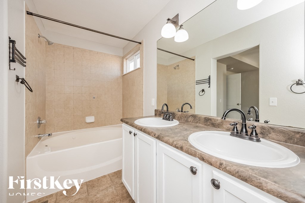 A bathroom with a tub, sink, and mirror.