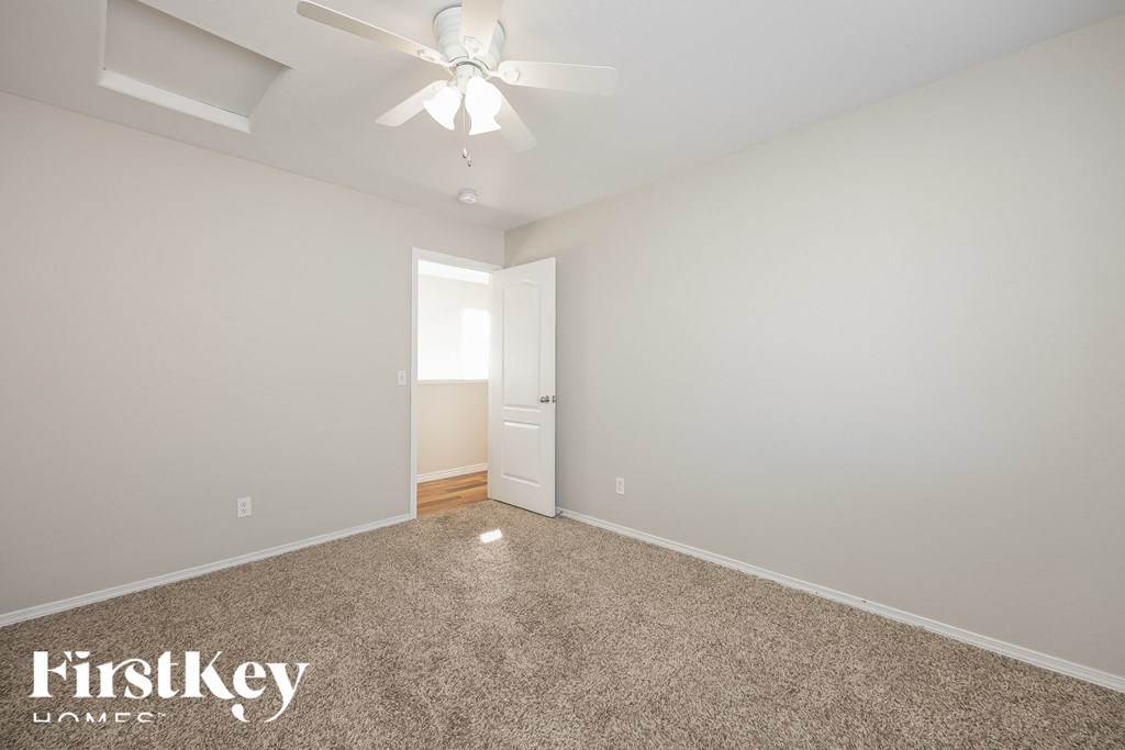 A room with a carpet floor and a ceiling fan.