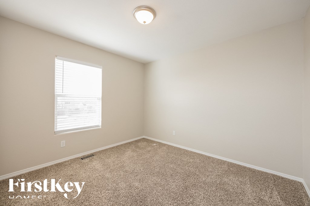 A room with a carpeted floor and a window with blinds.