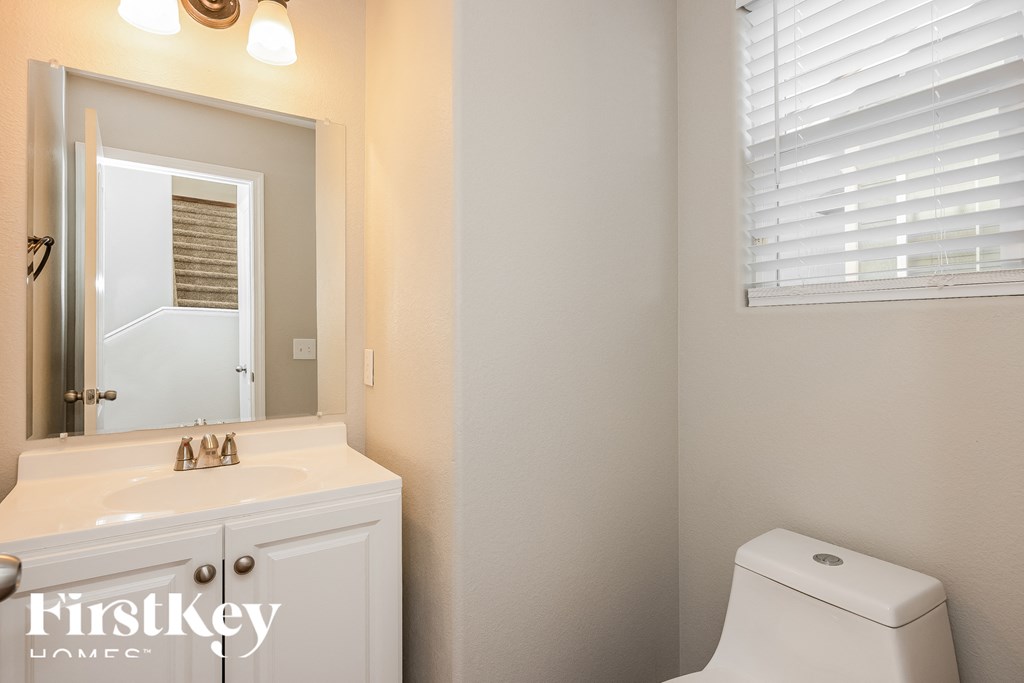 A white toilet in a bathroom with a white sink and a mirror.