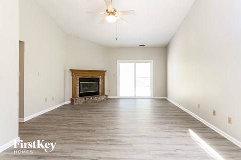 A spacious room with a fireplace and a ceiling fan.