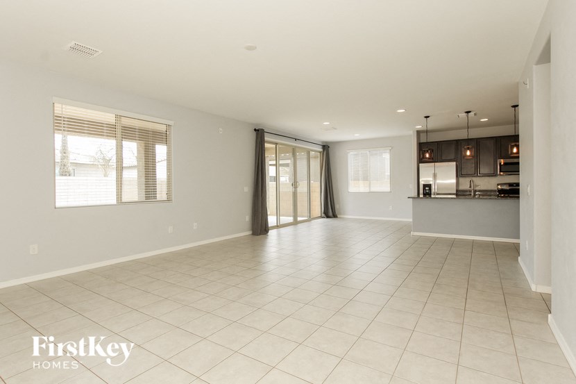 an empty living room with a kitchen in the background
