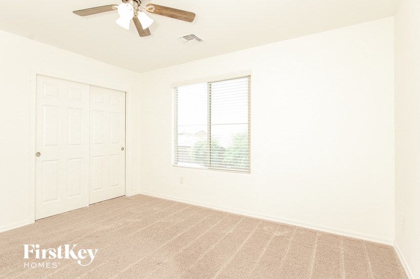 an empty room with a ceiling fan and a window