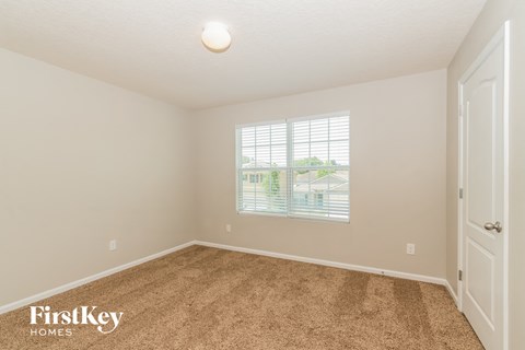 a spacious bedroom with carpet and a window
