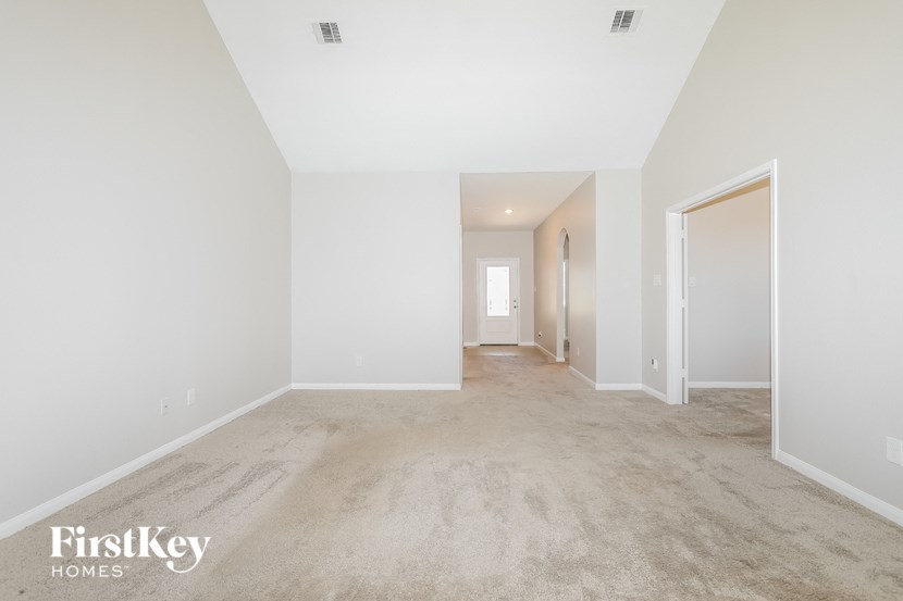 the living room and dining room of a house with carpet and white walls