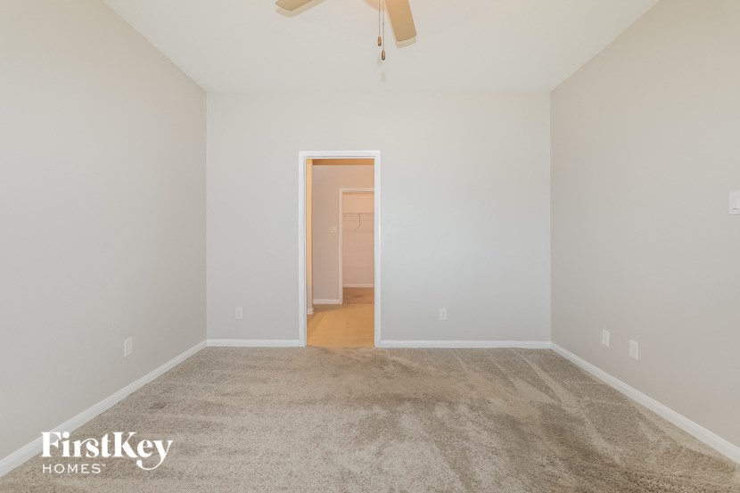 a bedroom with a carpeted floor and a door to a hallway