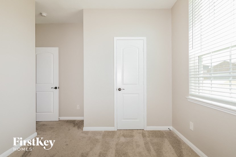 a bedroom with two doors and a window and a carpeted floor